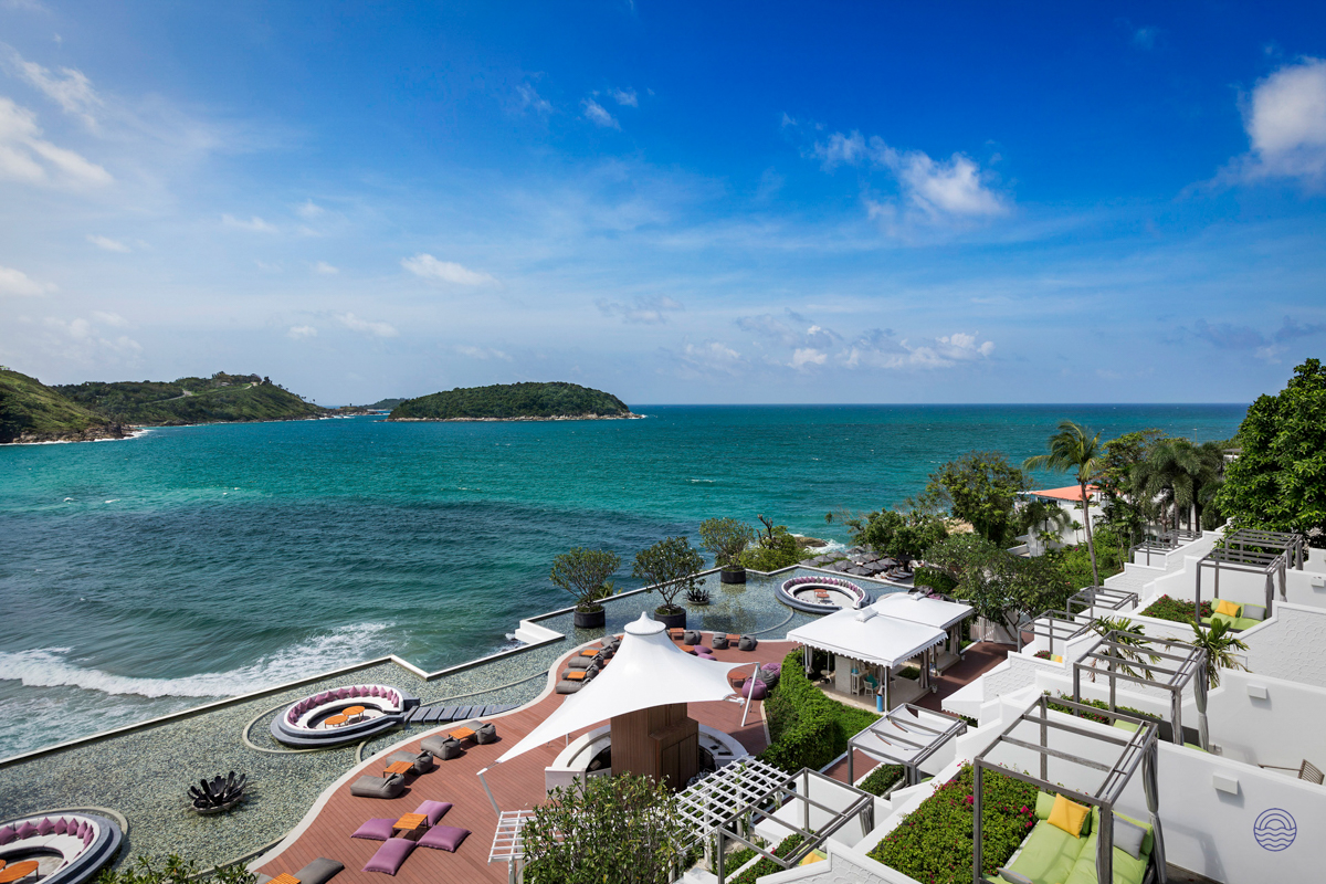 A luxurious resort terrace overlooks a beautiful turquoise bay and distant green islands in Phuket.