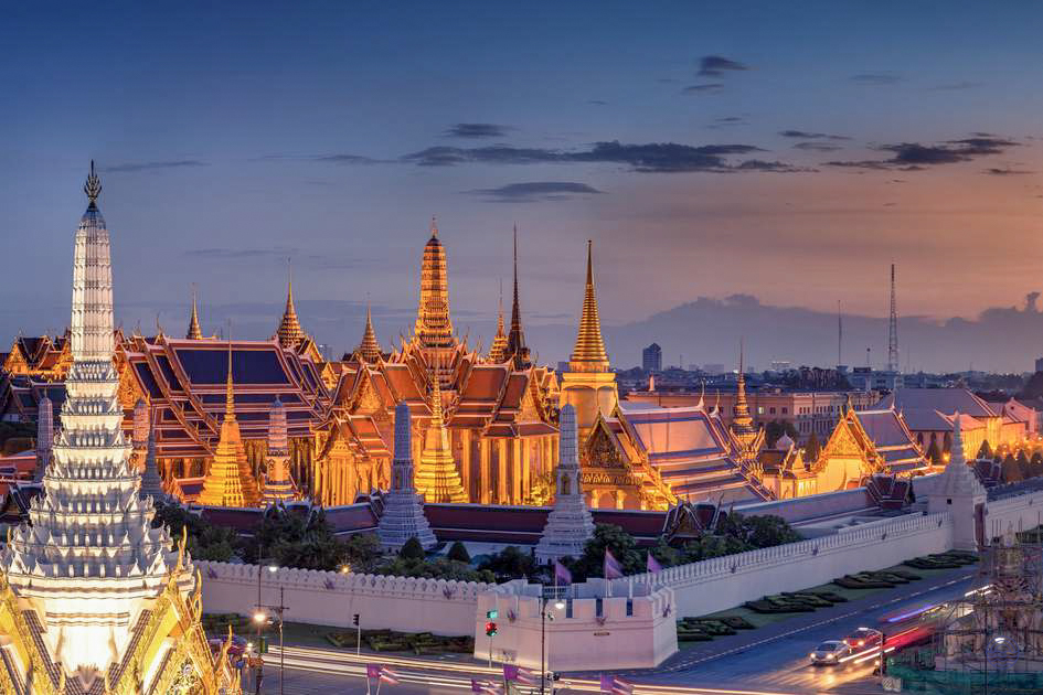 The Grand Palace in Bangkok shines with golden splendor against the twilight sky.