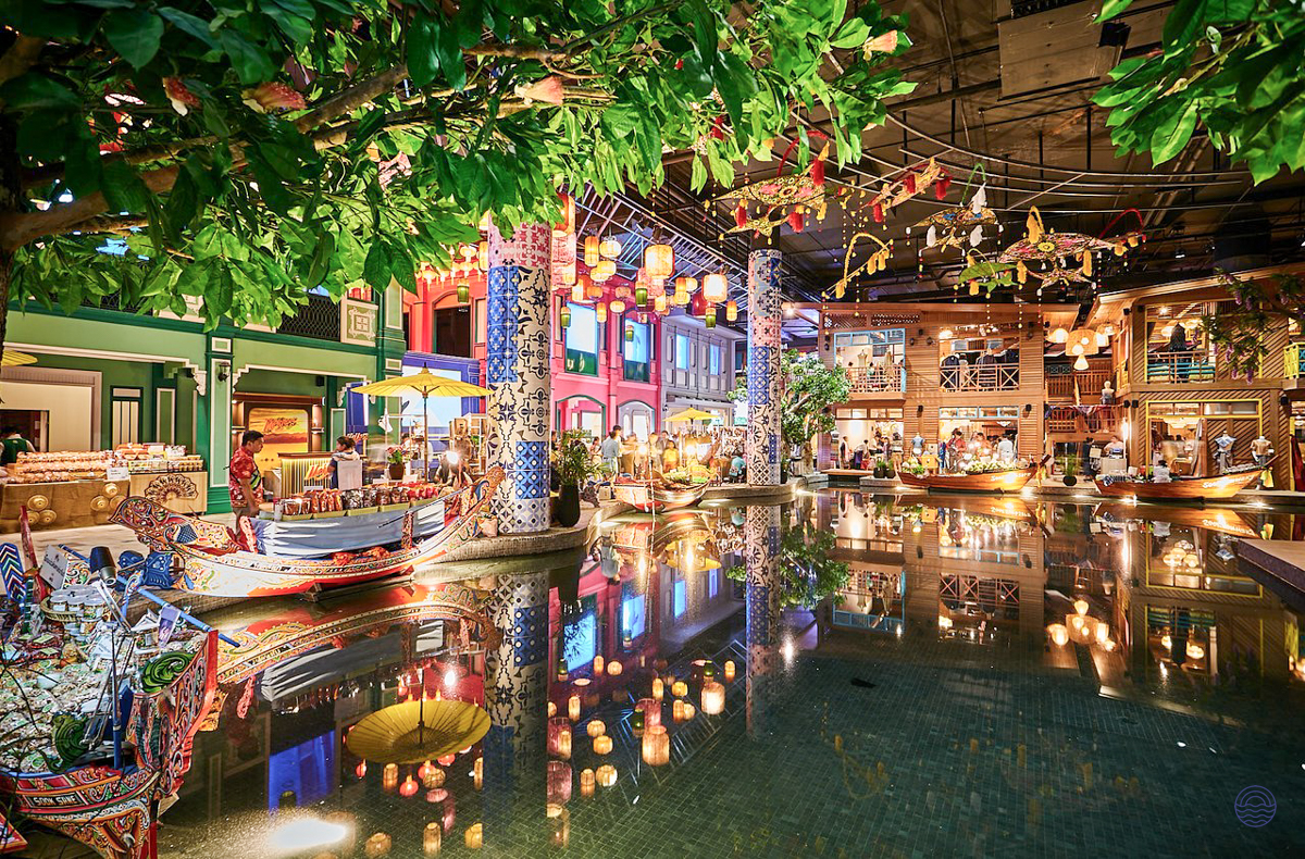 Colorful indoor market in Bangkok with traditional boats, glowing lanterns, and reflections on the water.