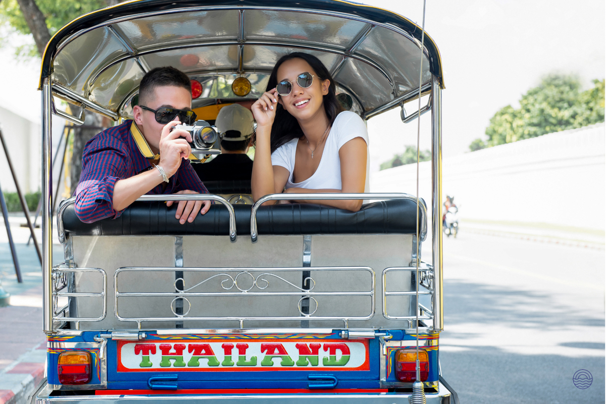 A happy couple enjoys a tuk-tuk ride through the vibrant streets of Bangkok, Thailand.