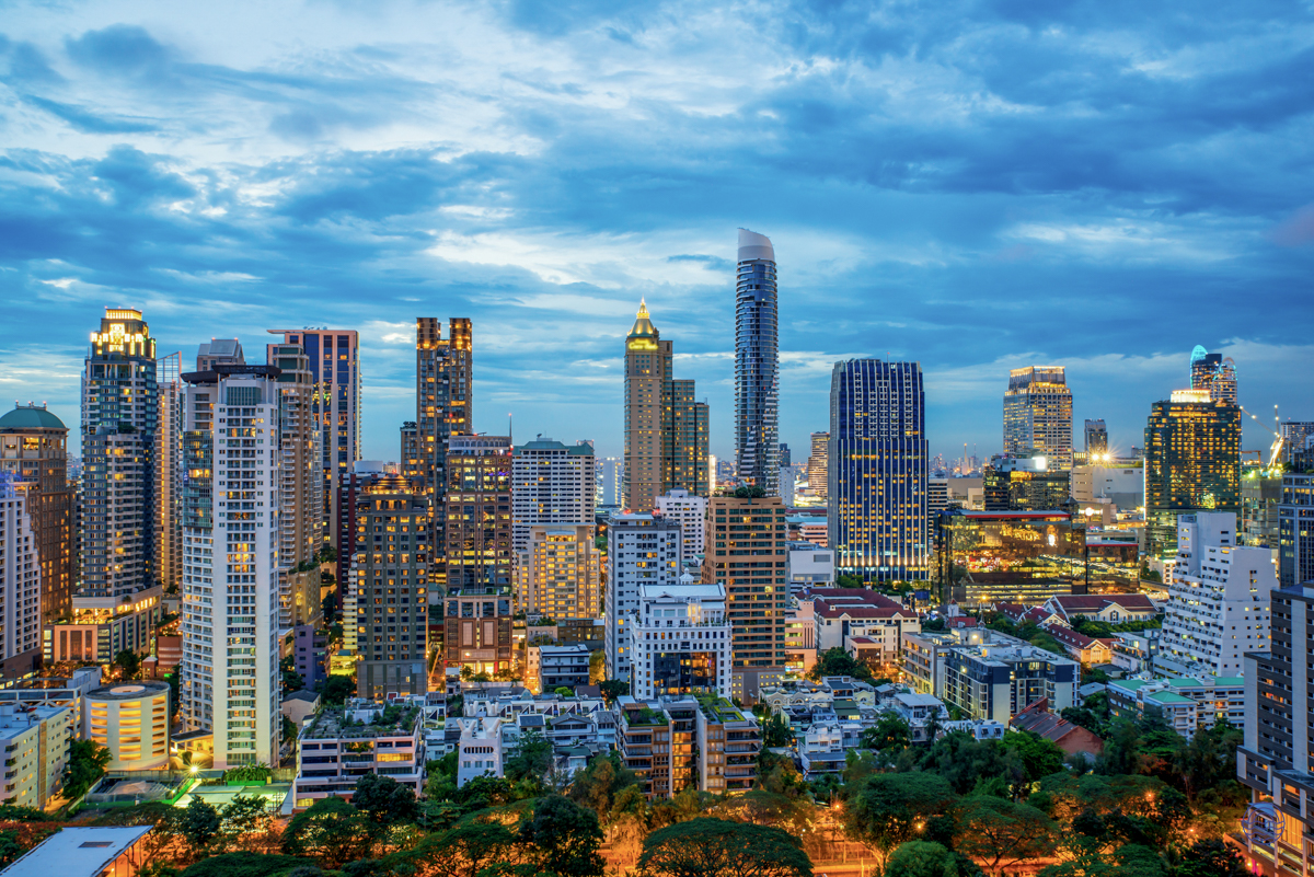 Modern skyscrapers illuminate the bustling Bangkok skyline as dusk settles over the vibrant city.