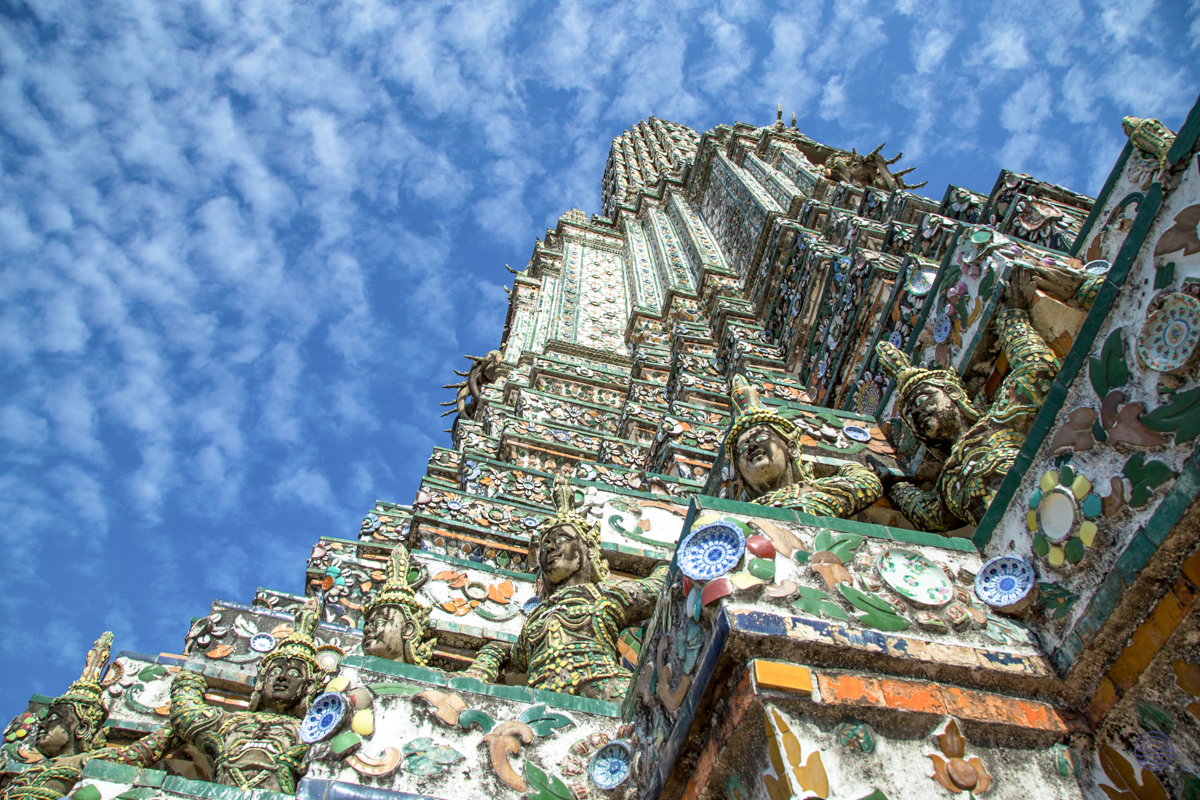 The magnificent prang of Wat Arun in Bangkok, adorned with colorful mosaics under a blue sky.