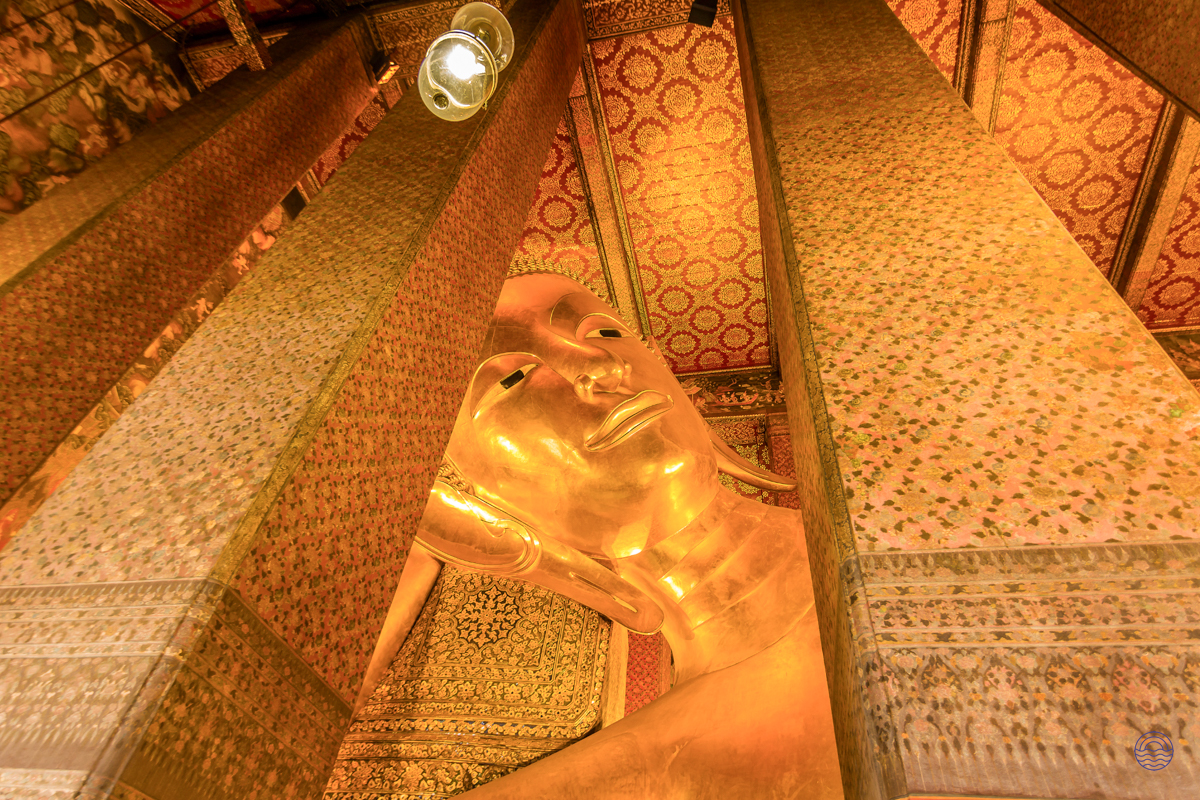 The magnificent golden reclining Buddha statue at Wat Pho in Bangkok, surrounded by ornate temple pillars.