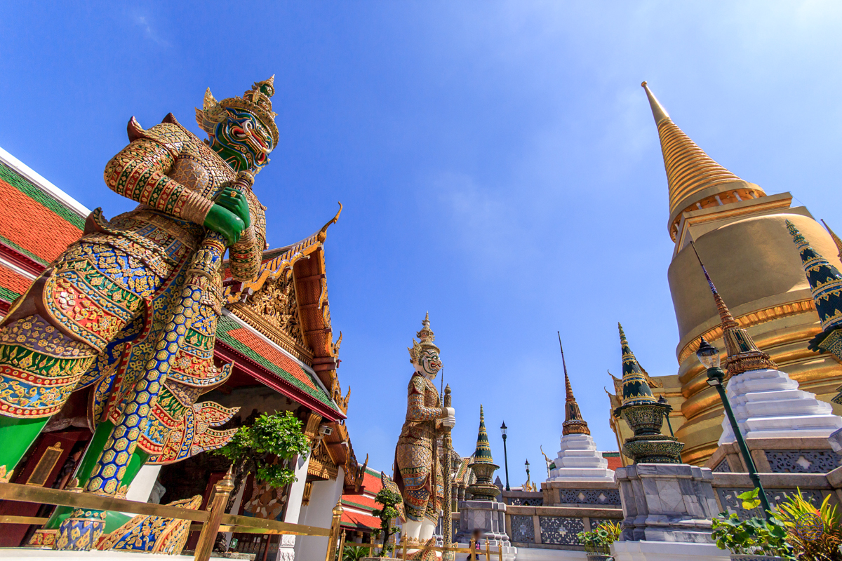 Giant guardian statues protect the sacred golden stupa at the Grand Palace in Bangkok.