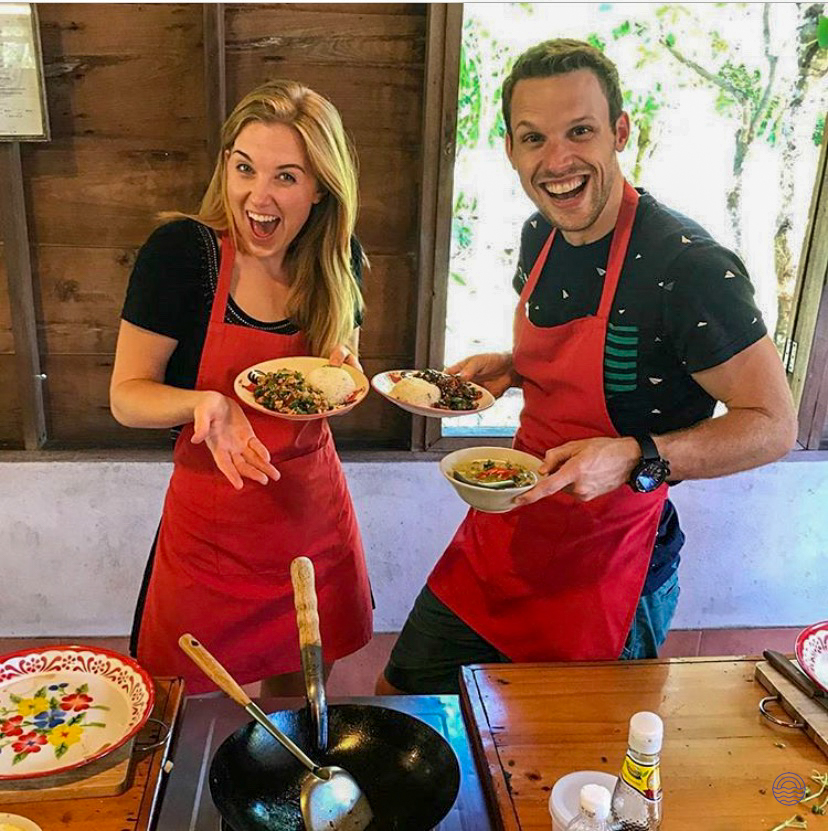 A happy couple proudly displays their freshly cooked Thai dishes during a hands-on cooking class in Chiang Mai.