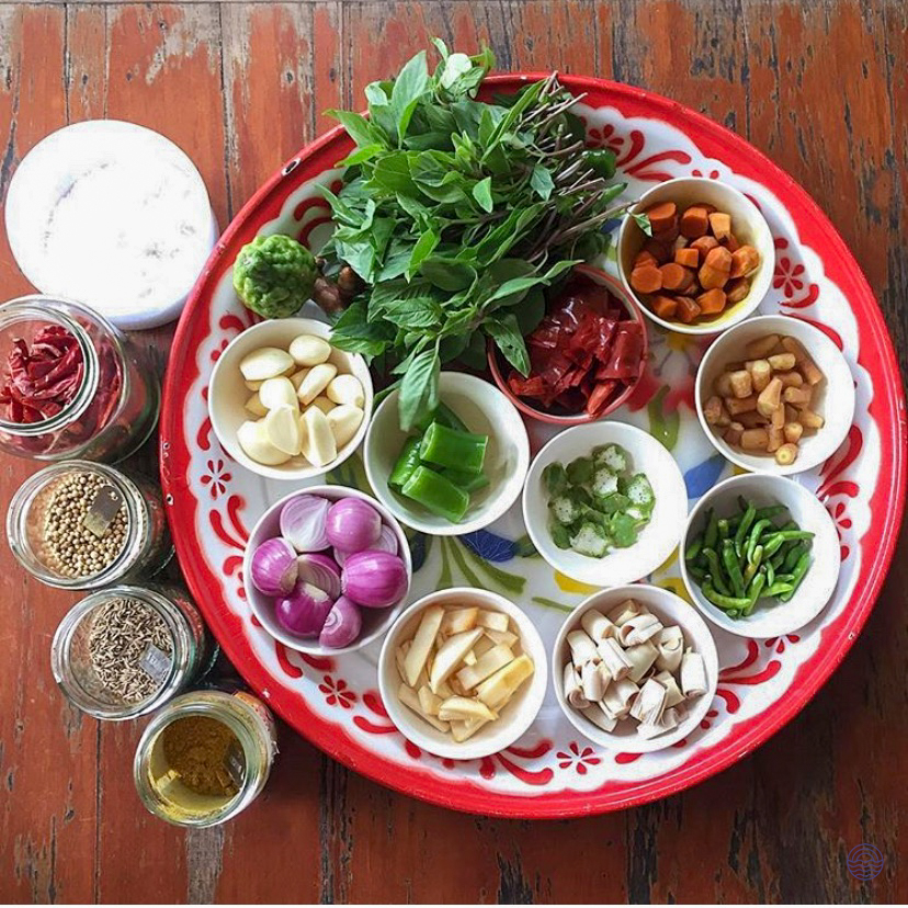 A colorful tray of fresh Thai cooking ingredients, including herbs, spices, and vegetables, in Chiang Mai.