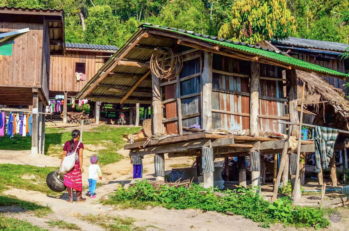 A woman and child walk past rustic stilt houses in a traditional Hmong village in Chiang Mai.