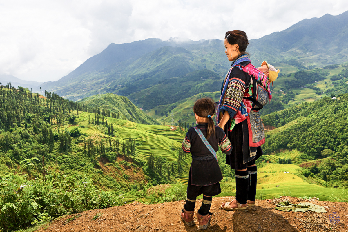 Hmong mother and child in traditional dress admire the beautiful green terraced mountains of Chiang Mai.