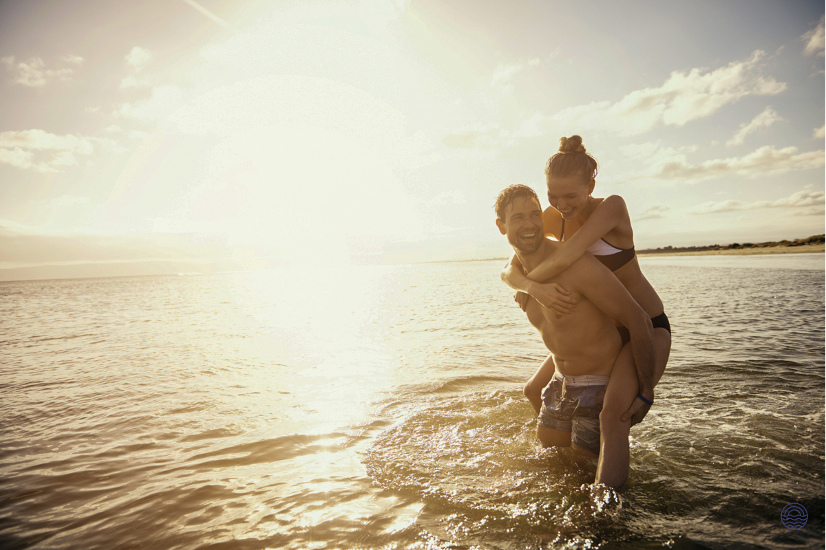 A happy couple enjoying a piggyback ride in the clear, sunlit waters of Koh Phi Phi.