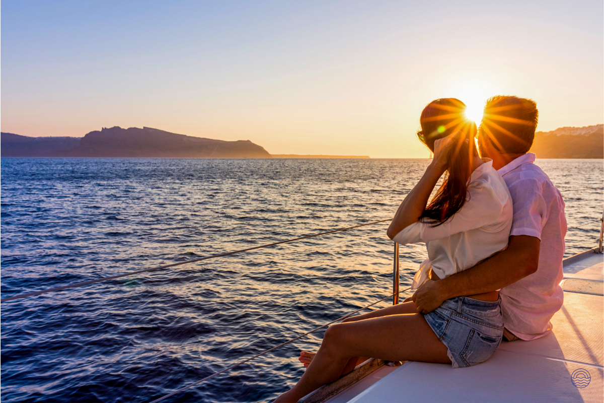 A couple embraces on a boat, watching a beautiful sunset over the Andaman Sea near Phuket.