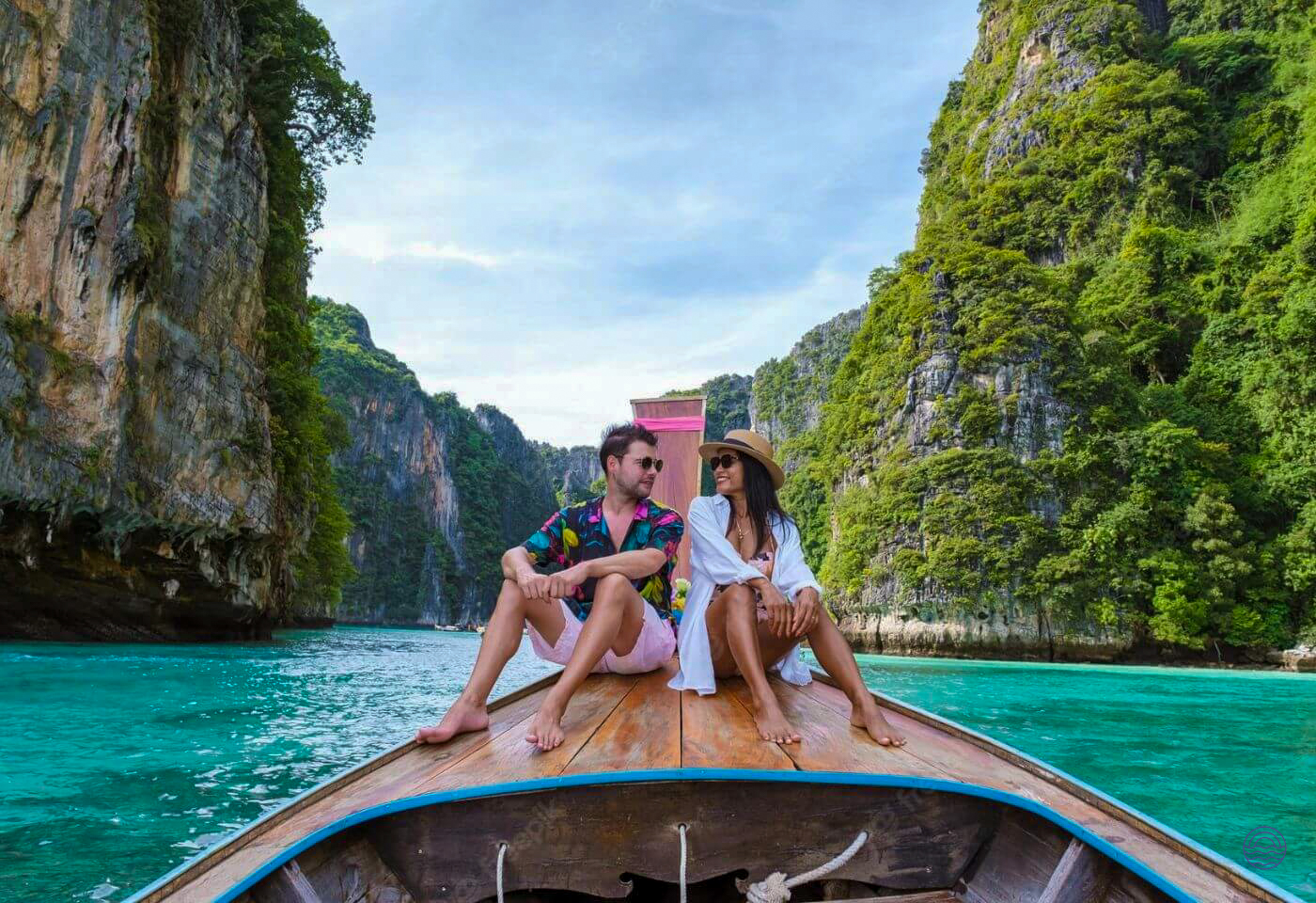 A couple enjoys a romantic longtail boat ride through stunning turquoise waters and towering limestone cliffs.