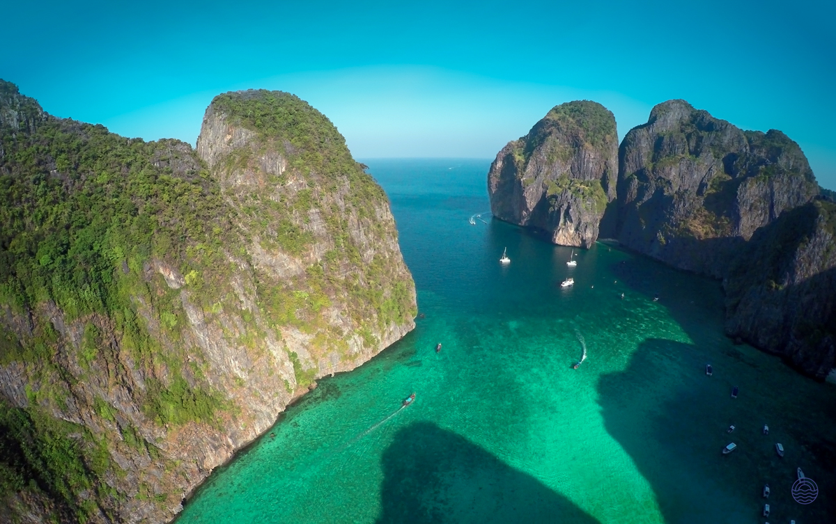 Majestic limestone cliffs rise from the emerald waters of Koh Phi Phi, dotted with boats.