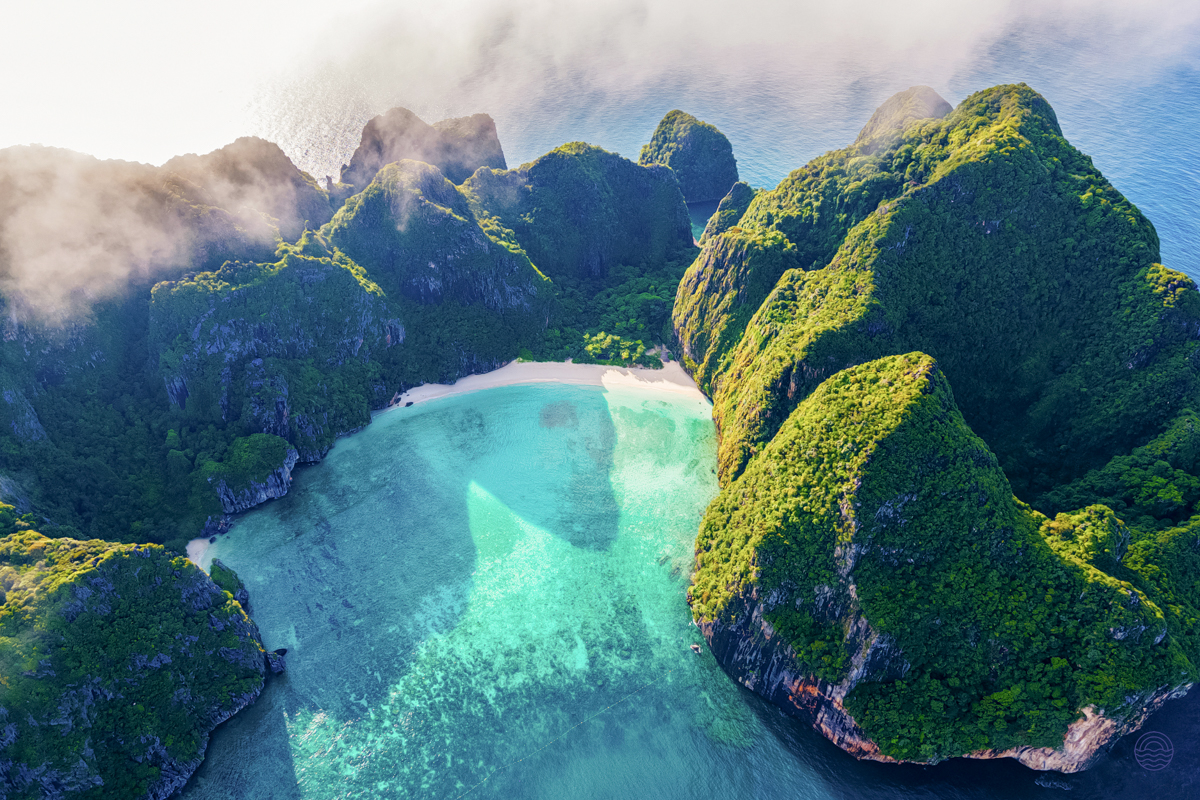 Serene aerial view of Maya Bay in Koh Phi Phi, showcasing lush cliffs and crystal-clear turquoise waters.