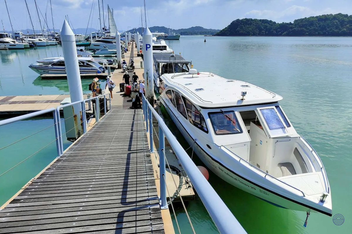 Tourists board a white speedboat at a pier with turquoise water and tropical islands in Koh Phi Phi.