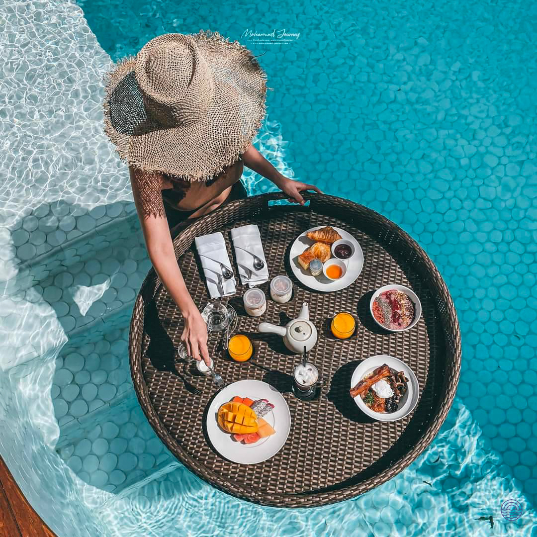 A person in a straw hat enjoys a luxurious floating breakfast in a private pool in Koh Samui.