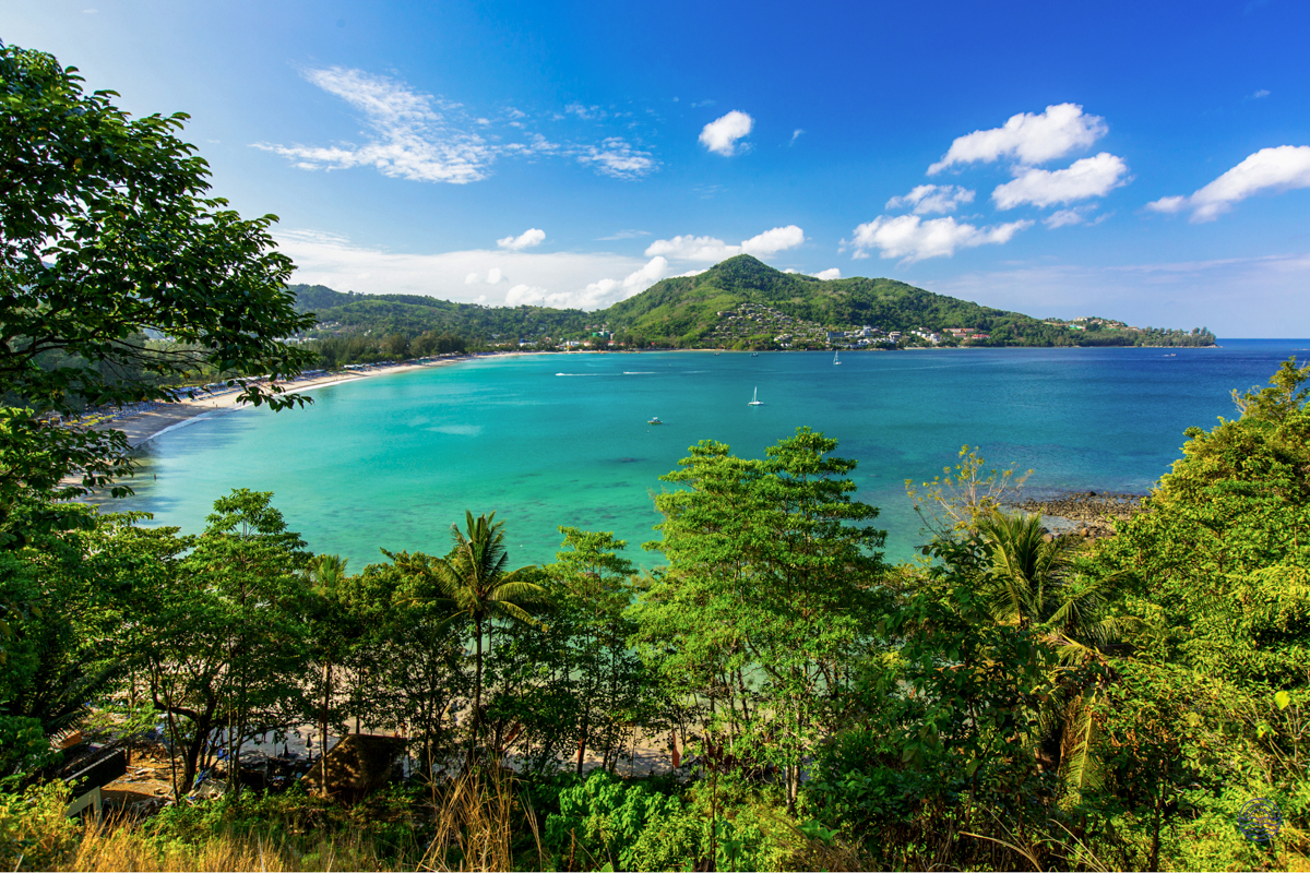 Stunning view of a vibrant turquoise bay with sandy beaches and lush green hills in Phuket.