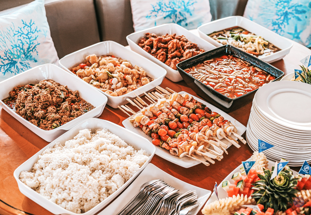 A sumptuous buffet of delicious Thai dishes, including rice, curries, and skewers, served onboard in Phuket.