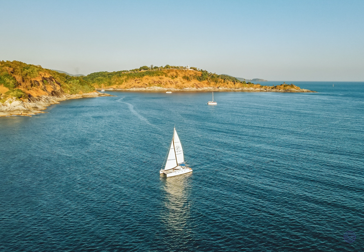 A white catamaran sails peacefully on the blue Andaman Sea near the coast of Phuket.