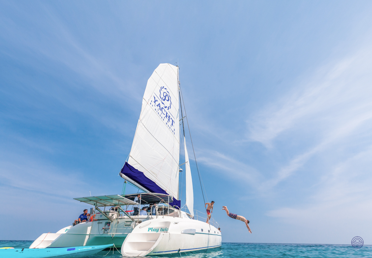 Adventurous travelers jump from a catamaran into the clear blue waters off Phuket, Thailand.