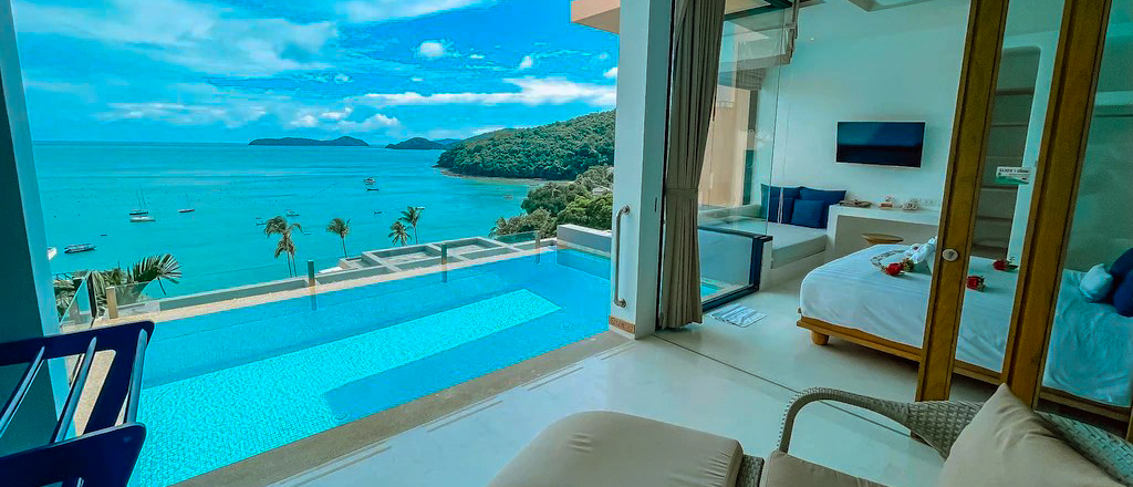Luxurious Phuket villa bedroom with an infinity pool, offering stunning turquoise ocean and island views.