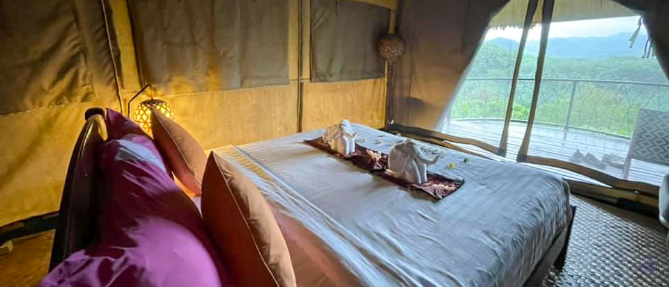Charming glamping tent with a comfortable bed, elephant towels, and a lush mountain view in Khao Sok.