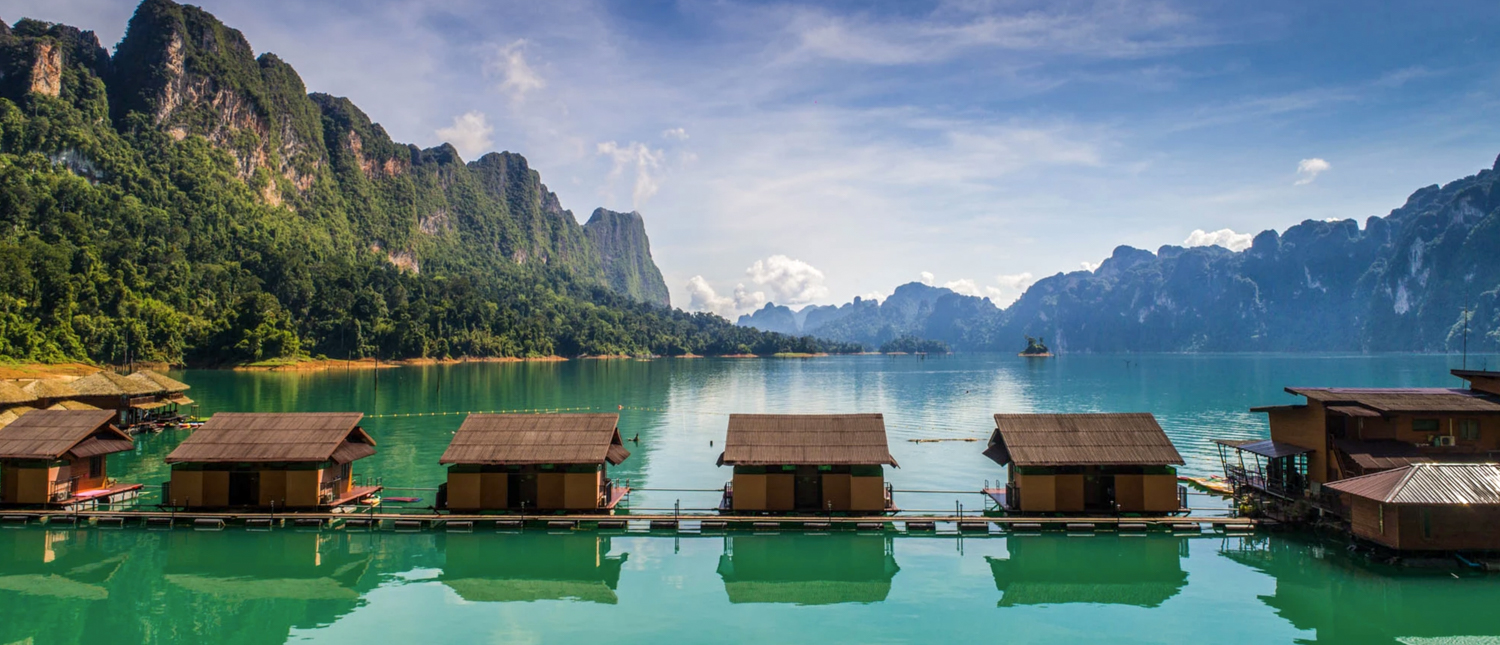 Floating bungalows on emerald Cheow Lan Lake, surrounded by towering limestone cliffs of Khao Sok National Park.