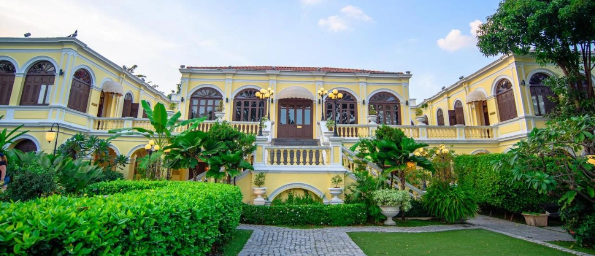 Elegant yellow colonial-style Praya Palazzo Hotel in Bangkok with lush tropical gardens.