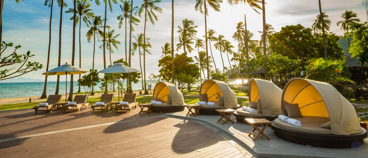 Empty sun loungers and covered daybeds at a sunny tropical beach resort in Koh Phi Phi.