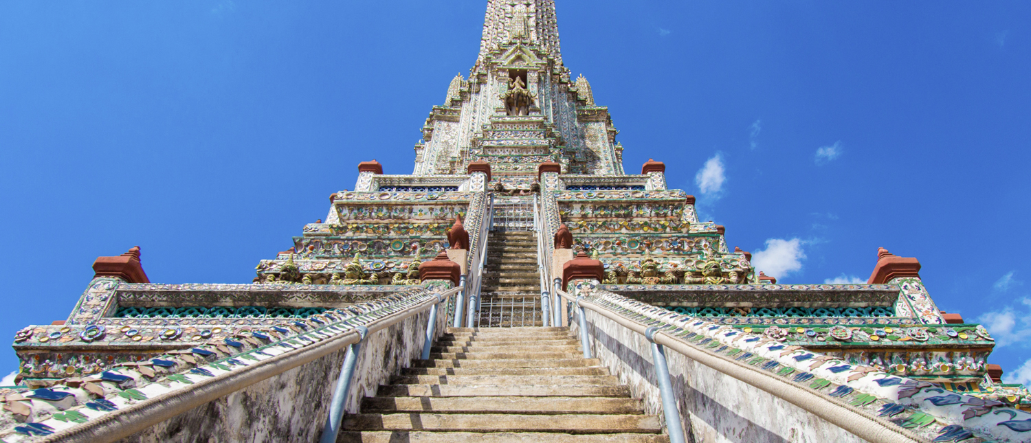Grand staircase leading up to the ornate, glittering Wat Arun temple in Bangkok.