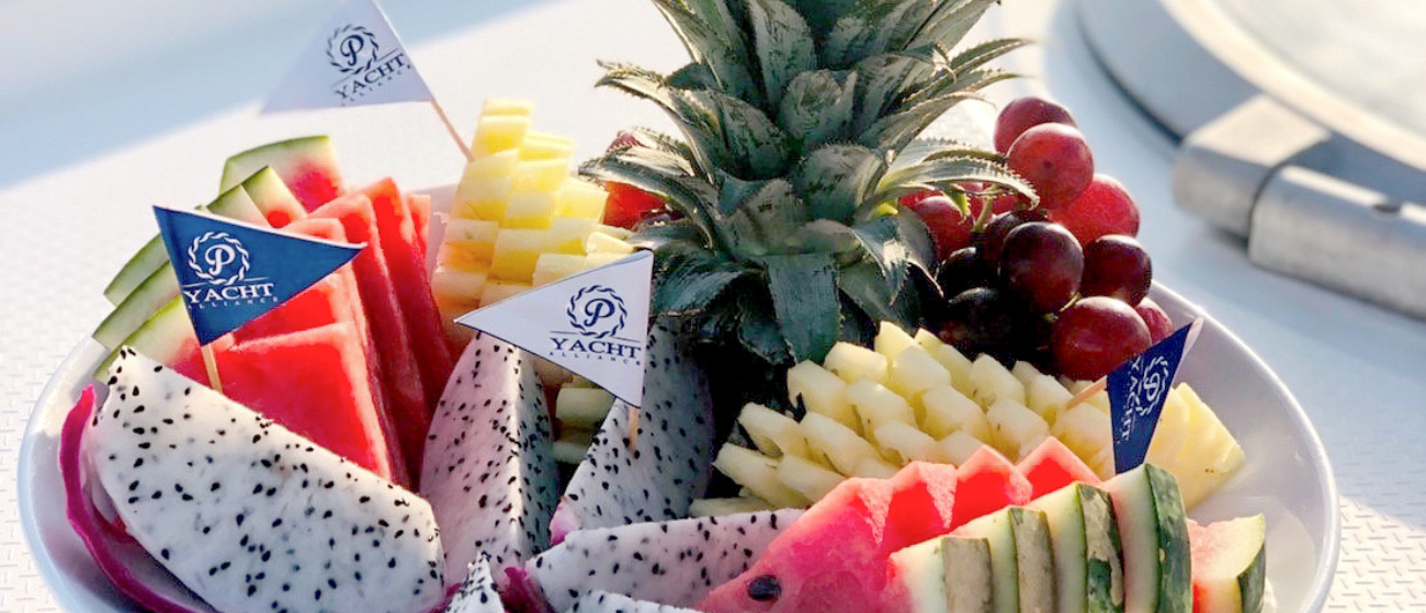 A refreshing plate of tropical fruits with watermelon, pineapple, and dragon fruit on a Phuket yacht.