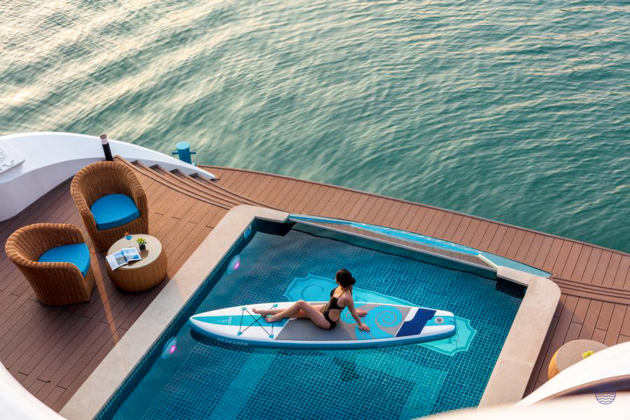 Woman relaxing on a paddleboard in a pool on a luxurious cruise ship deck in Halong Bay.