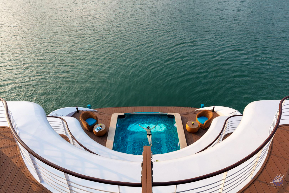 A person swims in a luxurious deck pool on a cruise ship overlooking Halong Bay.
