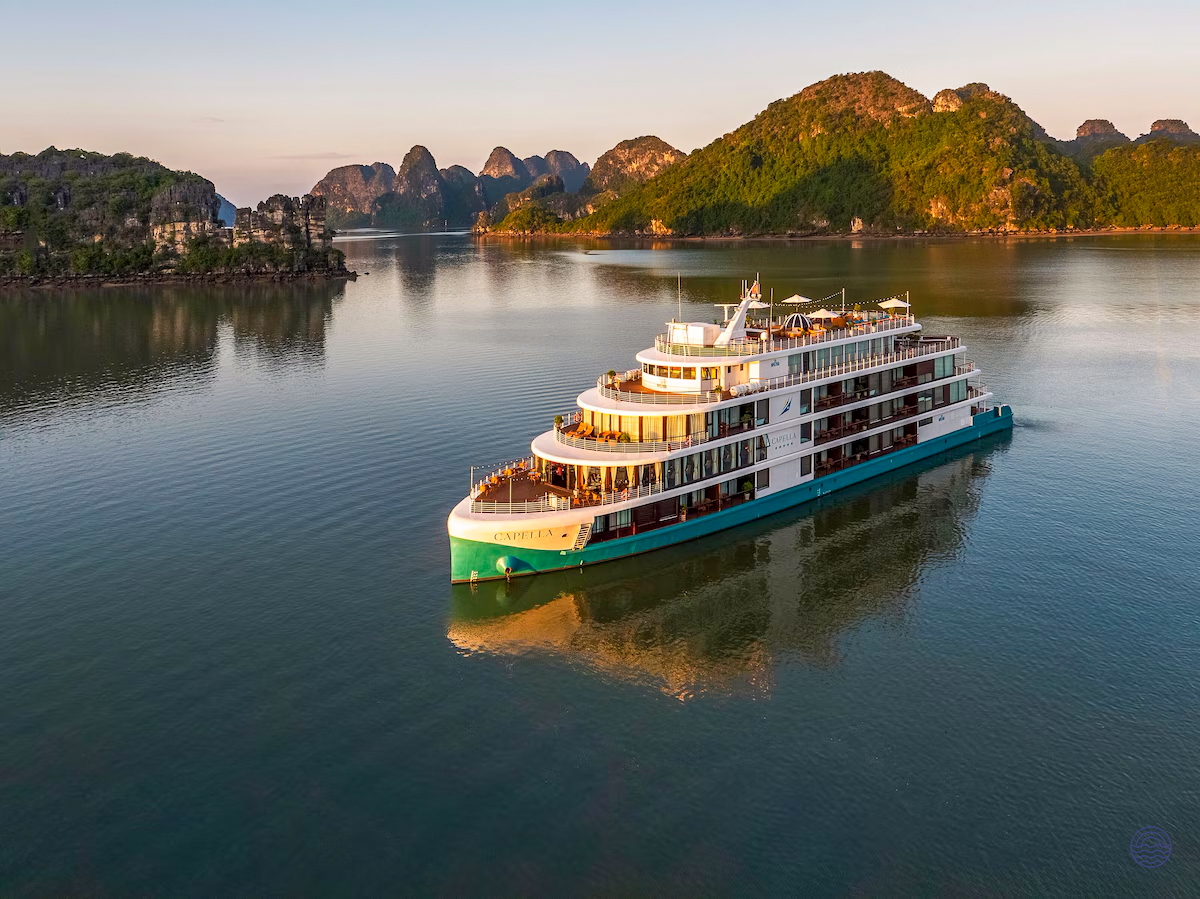 A multi-deck cruise ship sails calmly through Halong Bay's waters, surrounded by majestic limestone karsts.