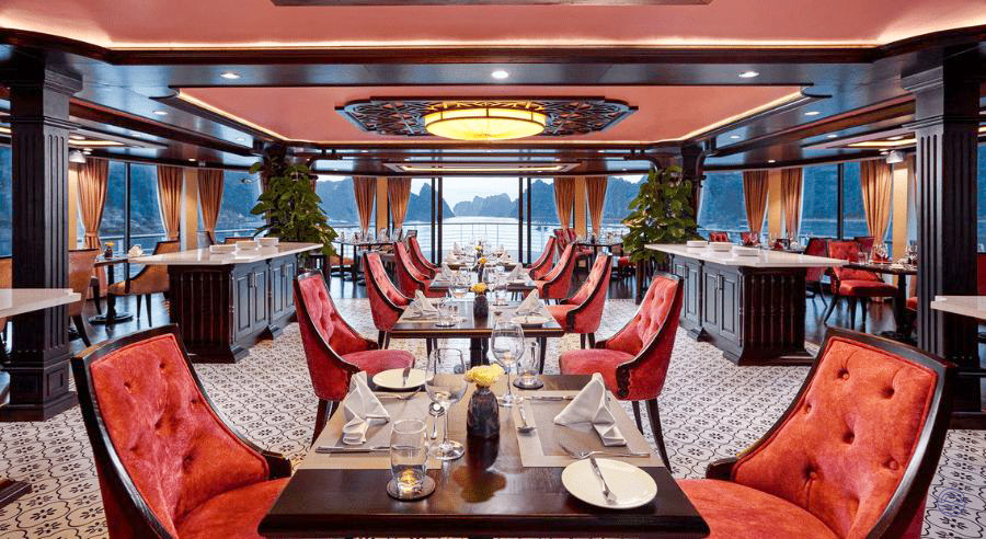 Elegant dining room on the Capella Cruise with red chairs and stunning views of Halong Bay.