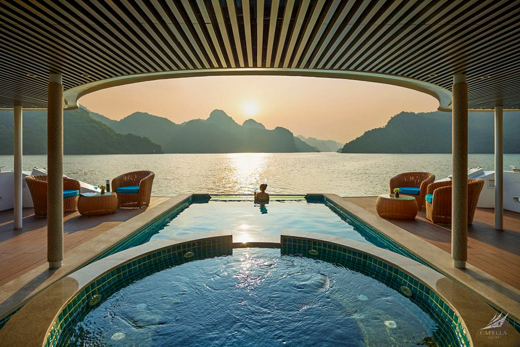 Relax in an infinity pool on a luxury cruise, watching the sunset over Halong Bay.