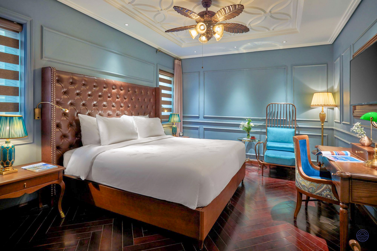 An elegant and luxurious hotel room in Hanoi with a large bed and stylish blue decor.
