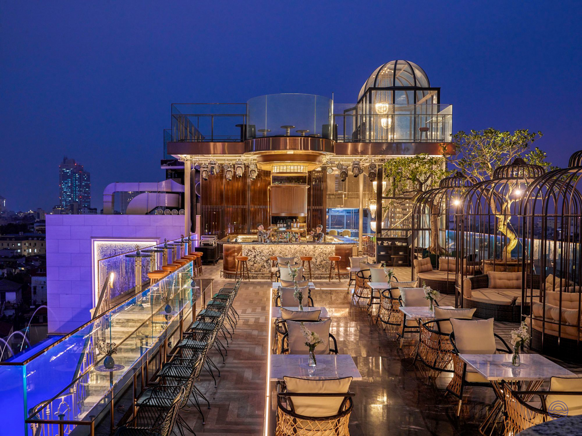 A luxurious rooftop bar in Hanoi at dusk, featuring elegant seating and a vibrant city view.