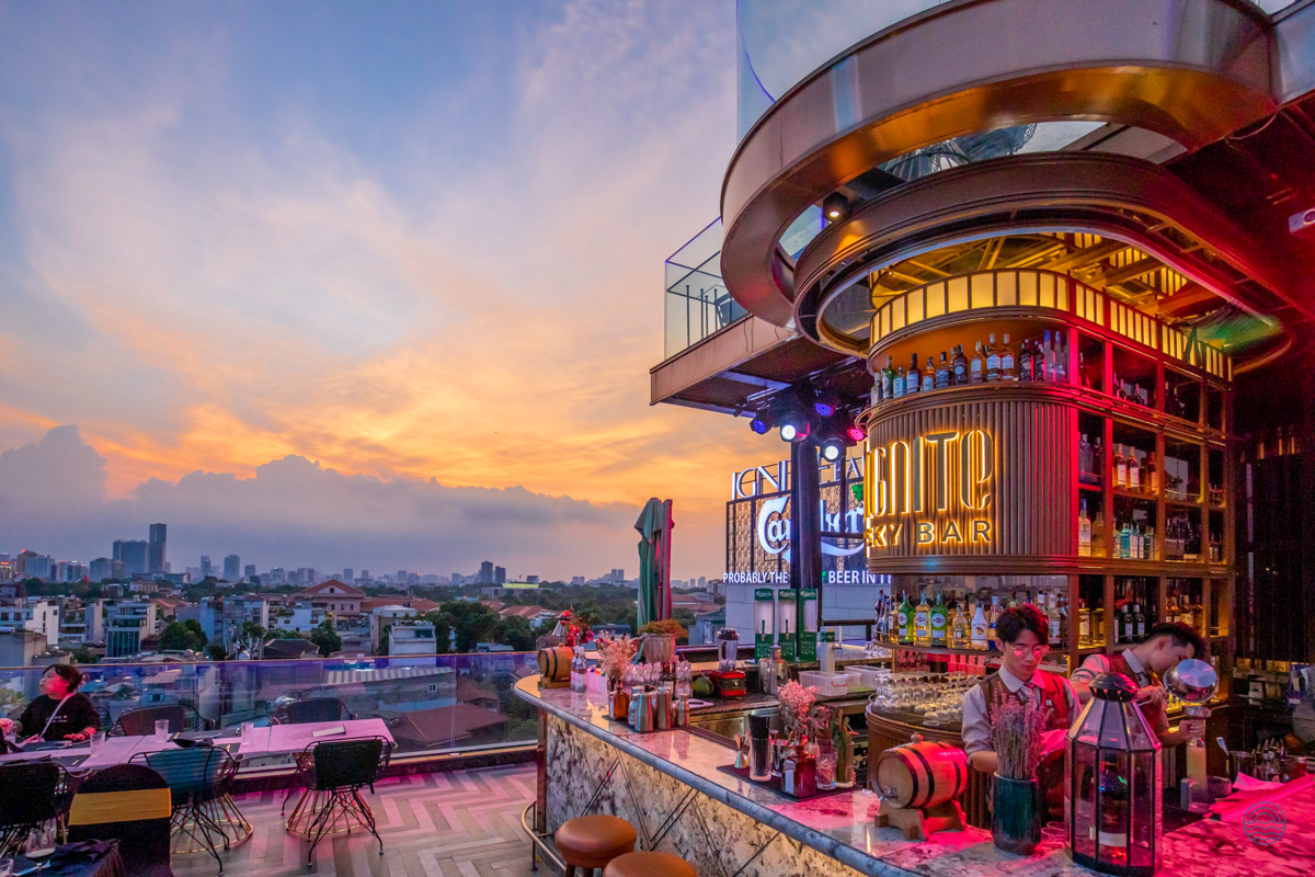 A vibrant rooftop bar at the Peridot Grand Hotel in Hanoi, offering city views at sunset.