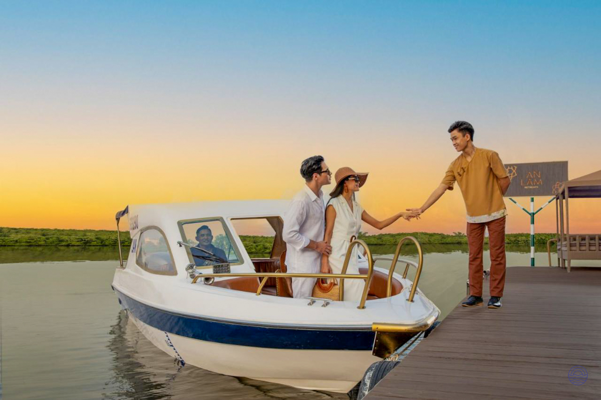 Guests disembarking a boat onto a pier, greeted by staff at sunset on the Saigon River.