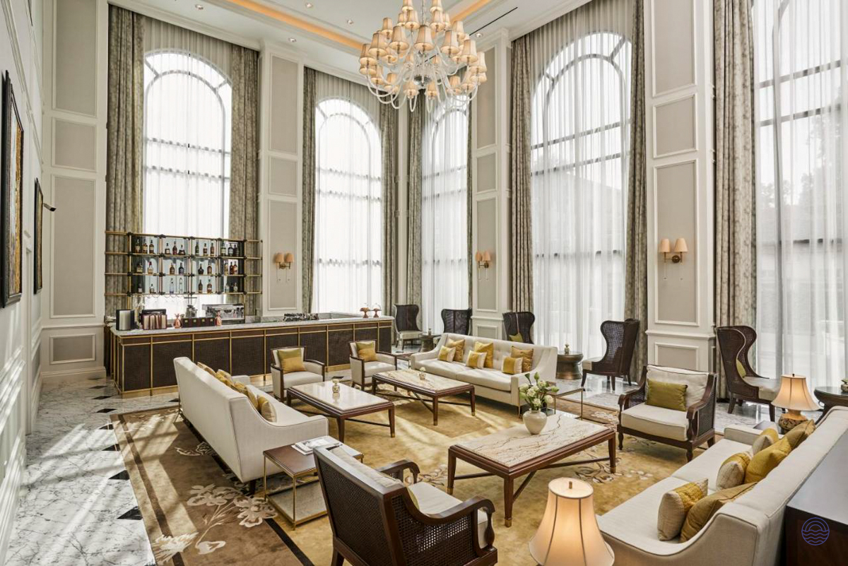 Elegant hotel lounge in Ho Chi Minh City featuring high arched windows, plush sofas, and a bar.