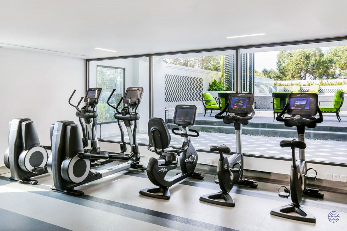 A luxurious hotel fitness center in Ho Chi Minh City, featuring modern exercise equipment and an outdoor view.