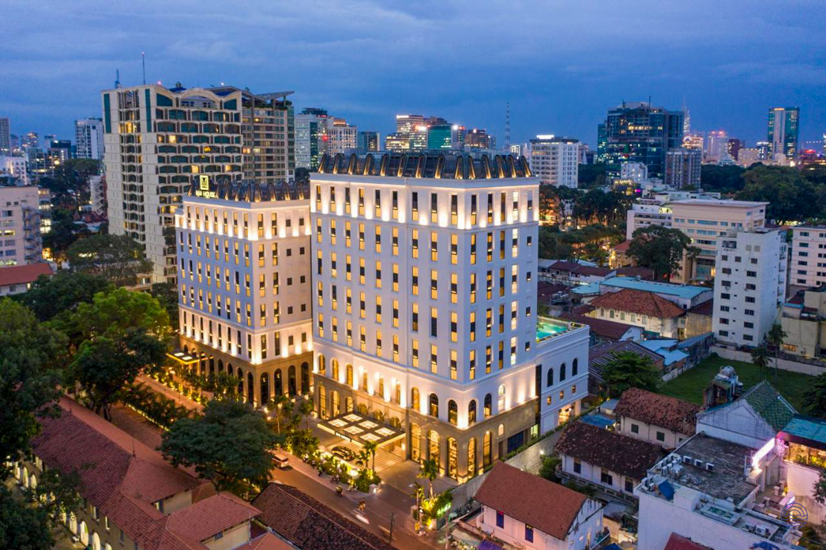 The luxurious Mai House Saigon Hotel stands illuminated at dusk in bustling Ho Chi Minh City.