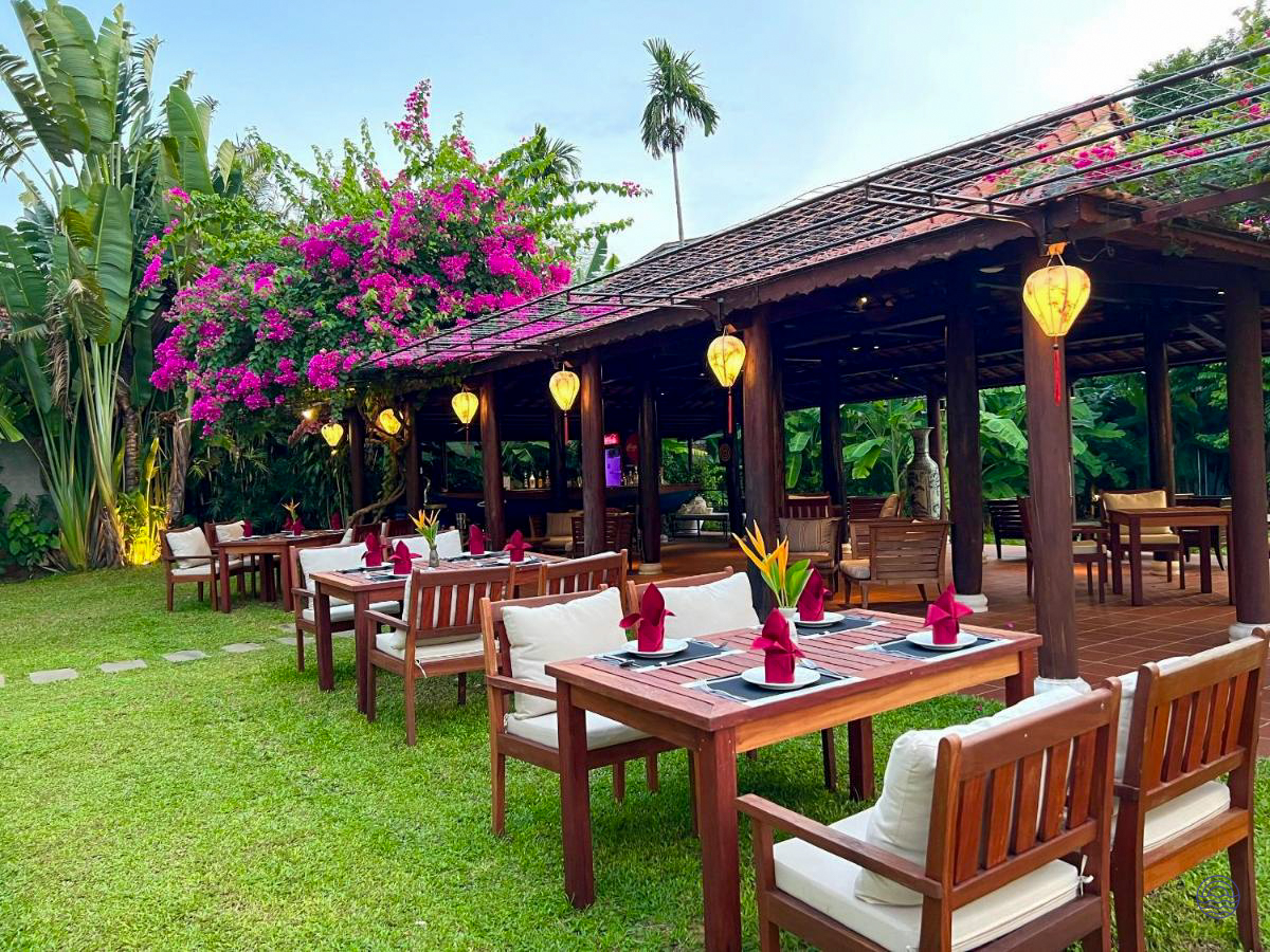 Beautiful outdoor dining area with wooden tables, pink bougainvillea, and lanterns in tropical Hoi An.