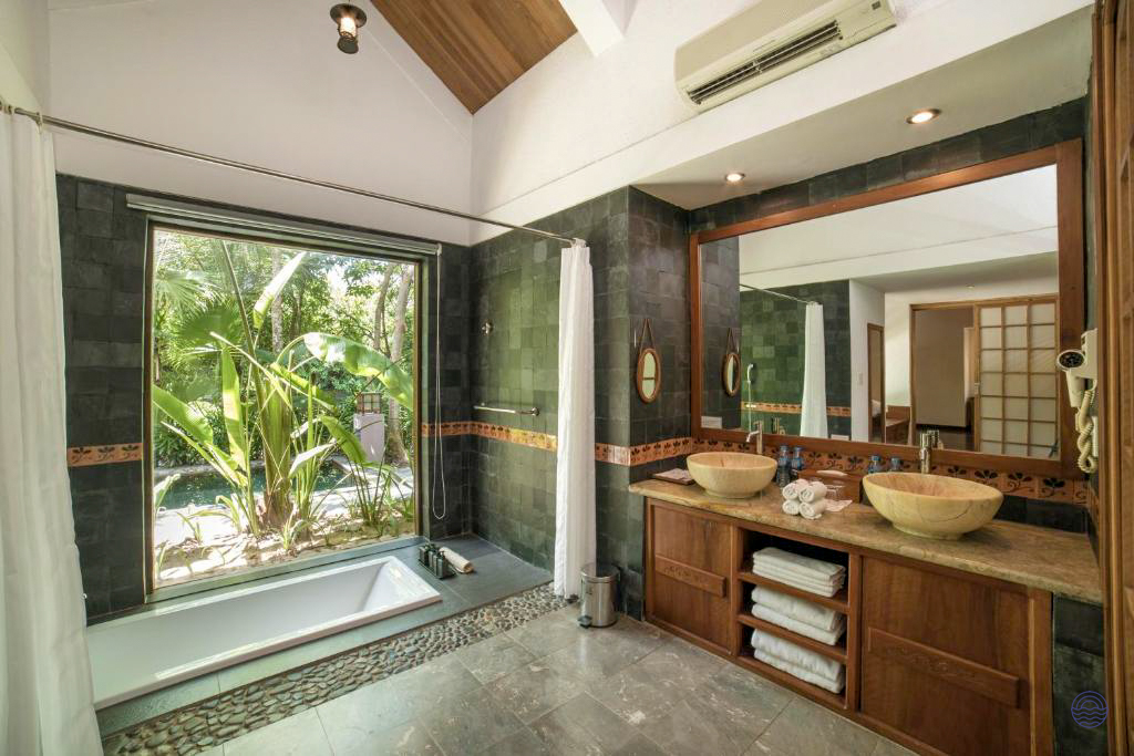 Luxurious bathroom at Pilgrimage Village in Hue, featuring a deep tub and lush tropical garden view.
