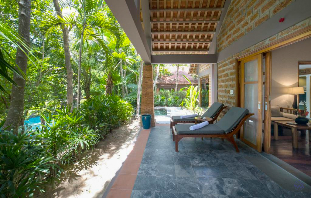 A luxurious resort patio with lounge chairs, lush tropical foliage, and a private pool.