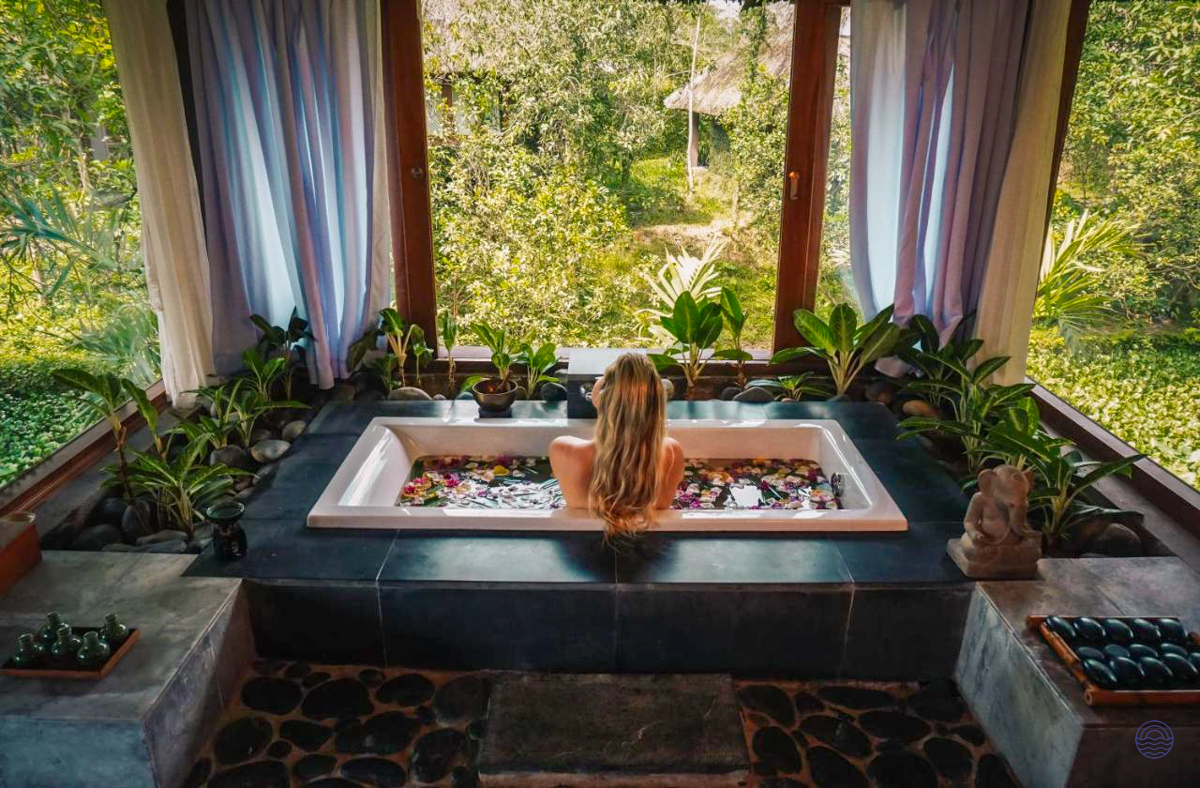 A woman relaxes in a luxurious flower-filled bathtub overlooking a lush jungle in Vietnam.