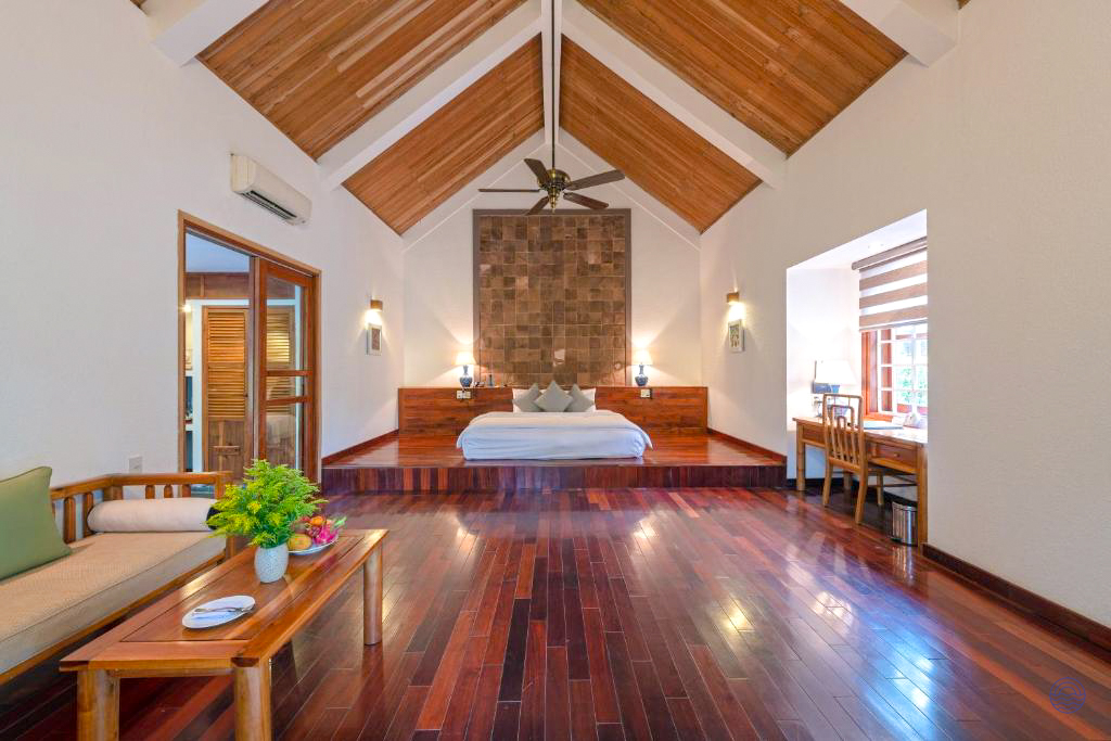 Spacious honeymoon suite in Hue with a high wooden ceiling, large bed, and comfortable seating area.