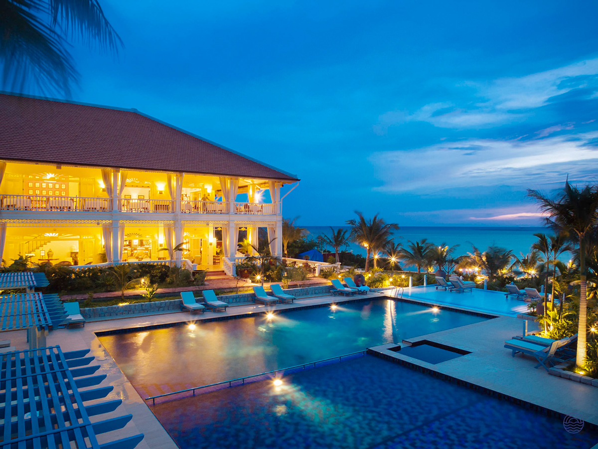 An idyllic resort in Phu Quoc with illuminated swimming pools and a grand building at dusk.