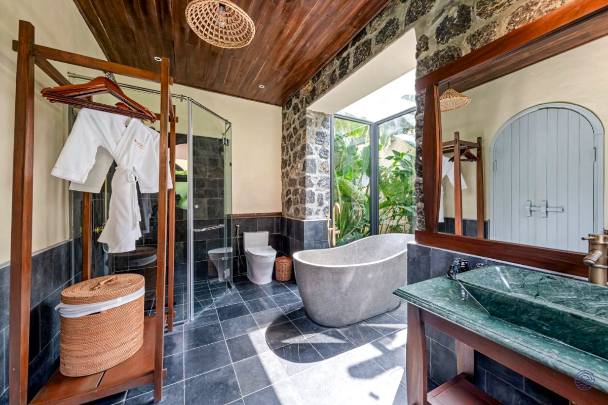 Elegant bathroom at Tam Coc Retreat featuring a stone tub, walk-in shower, and lush tropical garden views.