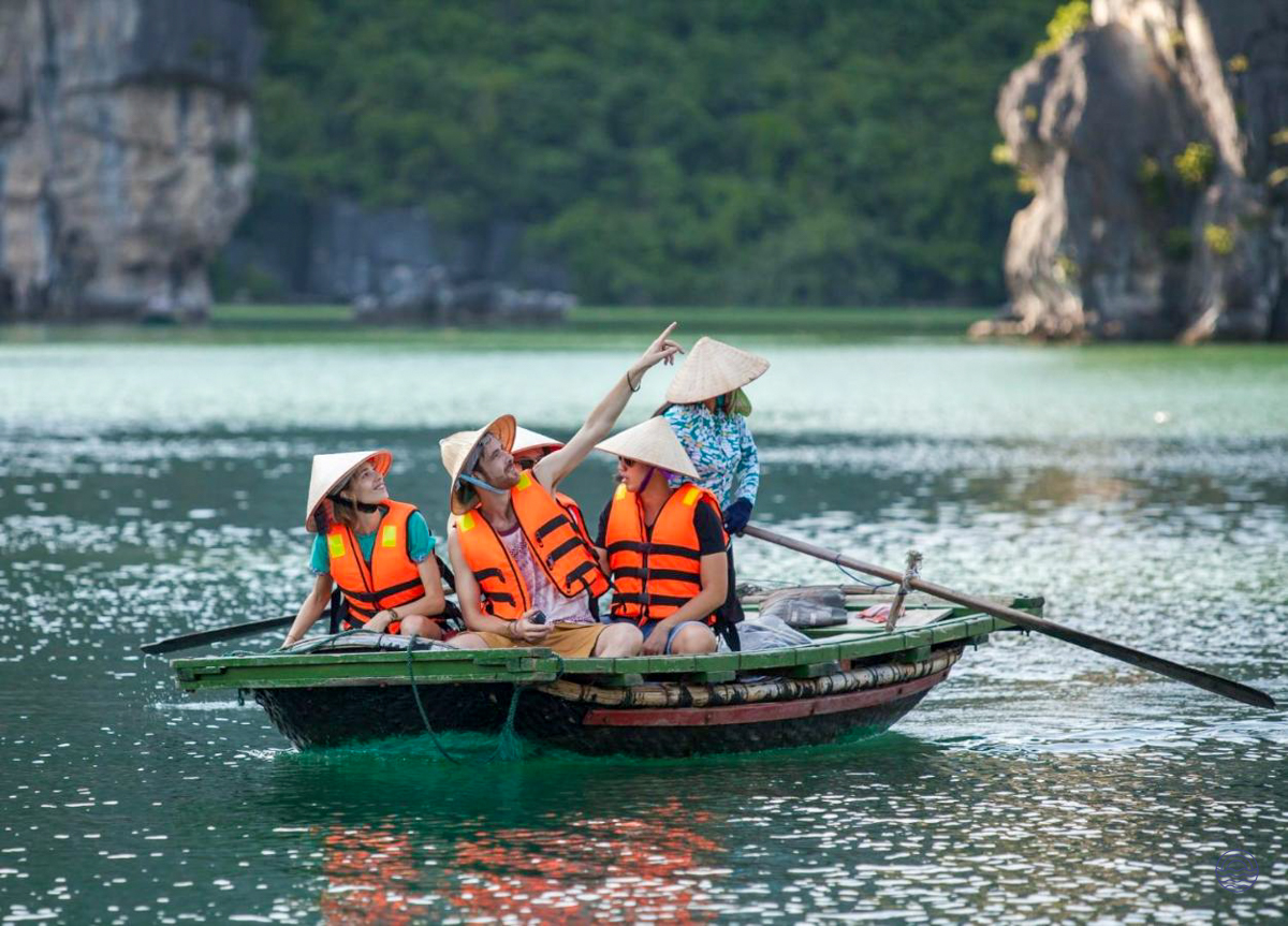 Exploring Ha Long Bay by traditional boat, tourists in conical hats admire the majestic limestone karsts.